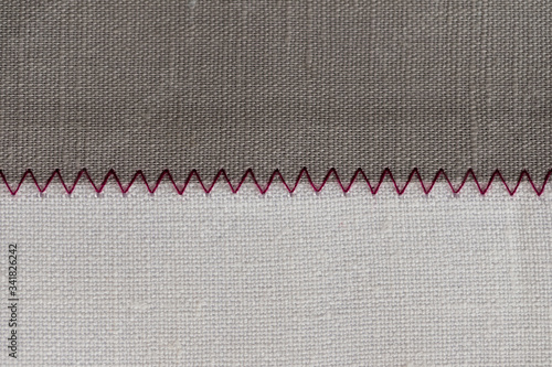 white and grey fabric stitched with a zigzag purple thread. Stitched pieces of fabric close-up. zigzag stitch.