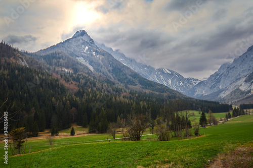 sun through clouds and green grass in the mountains of the alps