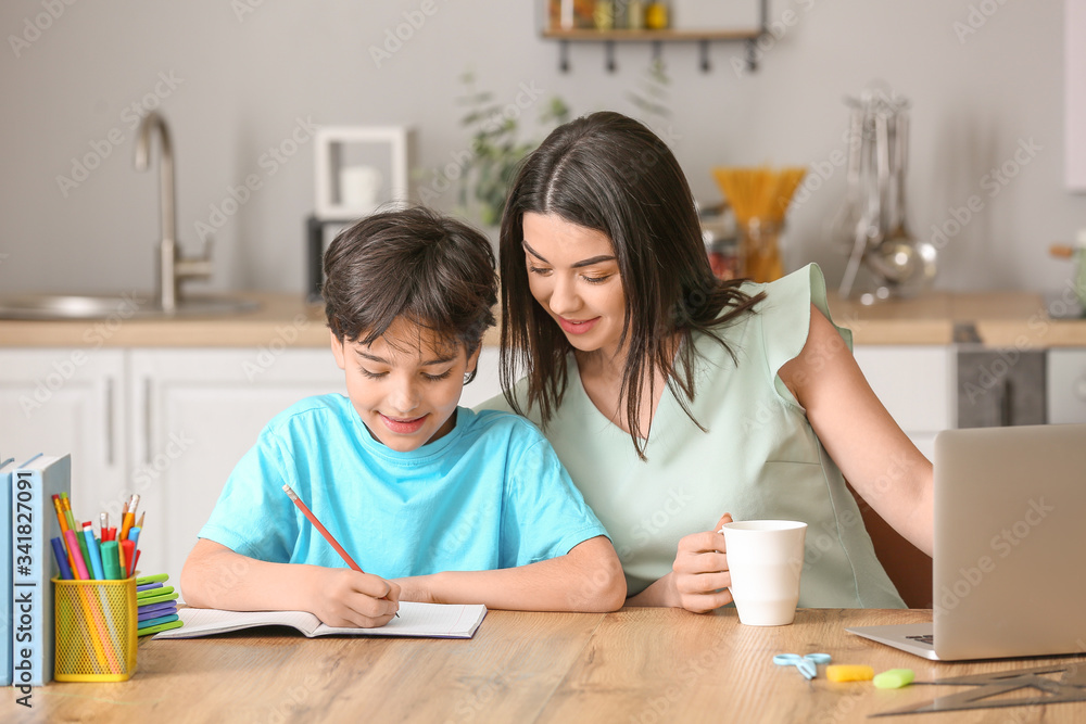 Little boy with his mother doing homework in kitchen Little boy with his mother doing homework in kitchen