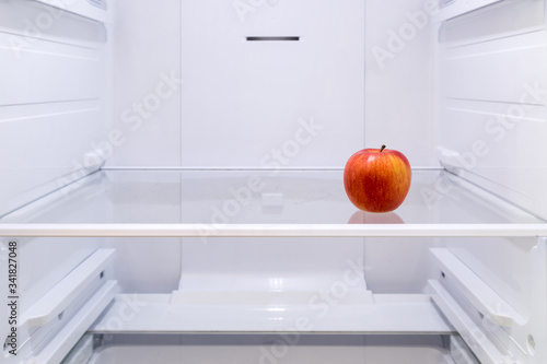 one red Apple on a shelf in an empty refrigerator
