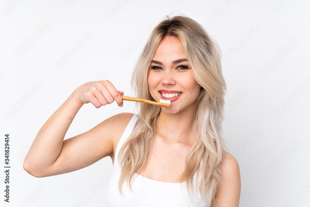 Teenager blonde girl over isolated white background with a toothbrush Teenager blonde girl over isolated white background with a toothbrush
