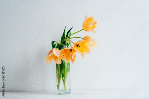 Holiday card. A bouquet of orange tulips in a vase.