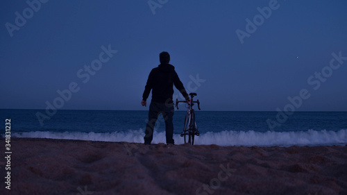 Cyclist man  on the beach watching the sea during a sunset. Barcelona, Spain.