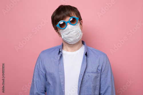 young caucasian man wearing a protective mask isolated on pink background photo