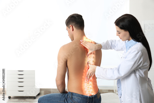 Professional orthopedist examining man in medical office. Spinal pain photo