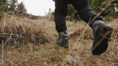 Legs of man walking along trail in forest. Сamera follows from a low point. Rear view. Stabilized footage photo