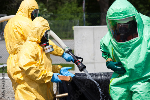 Obraz na plátně Two men in protective gear decontaminating another man