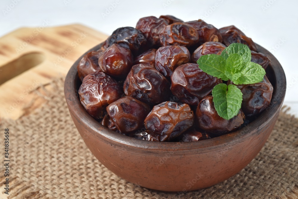 dried date and green mint in a bowl on white wooden table. dried date and green mint in a bowl on white wooden table.