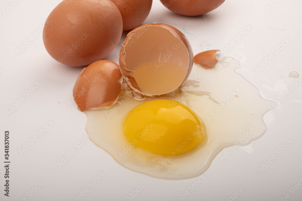 A broken chicken egg and scattered eggs on a white background. Close up. A broken chicken egg and scattered eggs on a white background. Close up.