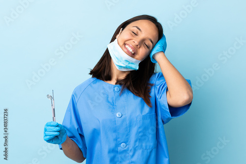 Young brunette mixed race dentist woman holding tools over isolated background laughing