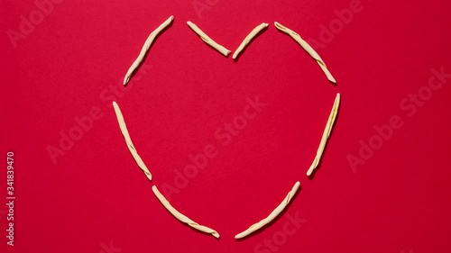 Italian fileja pasta on red background shaped as a heart. Concept for food love and pleasure. 4K stop motion animation seamless loop
