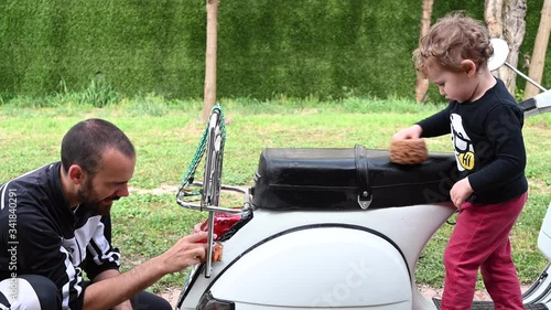 Dad and son washing together a typical Italian motorcycle. Family activities.