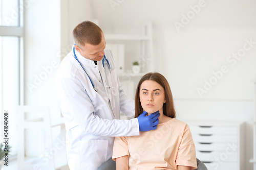 Endocrinologist examining throat of young woman in clinic