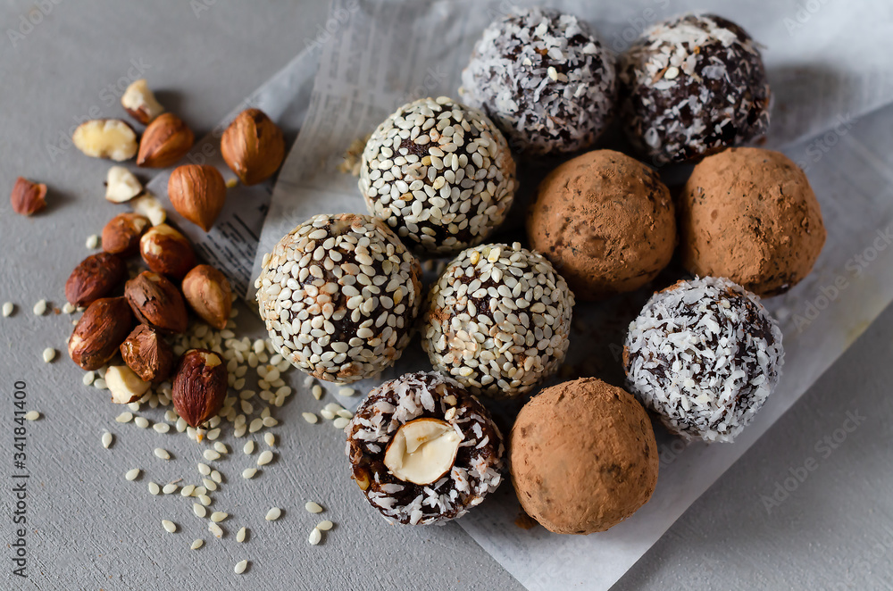 Raw vegan energy balls with hazelnut on a gray background. Natural sweets from nuts and dried fruits in coconut, cocoa and sesame seeds, close-up. Sugar-free and gluten-free sweets, raw food desserts. Raw vegan energy balls with hazelnut on a gray background. Natural sweets from nuts and dried fruits in coconut, cocoa and sesame seeds, close-up. Sugar-free and gluten-free sweets, raw food desserts.