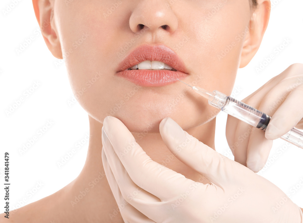 Young woman receiving filler injection on white background
