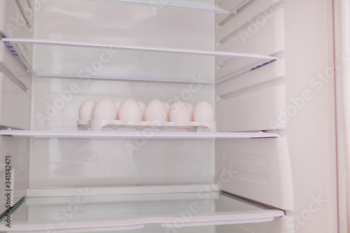 Chicken eggs standing on the empty shelf of the refrigerator in the egg tray