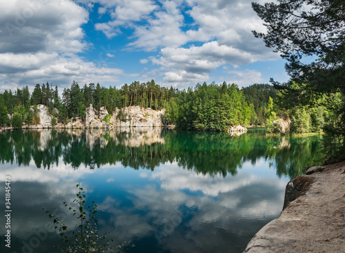 Lake with beautiful reflections of clouds in blue sky and ancient pines growing in rock city Adrspach, National park of Adrspach, Czech Republic
