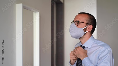 Young businessman getting ready facing mirror and adjusting his protection mask