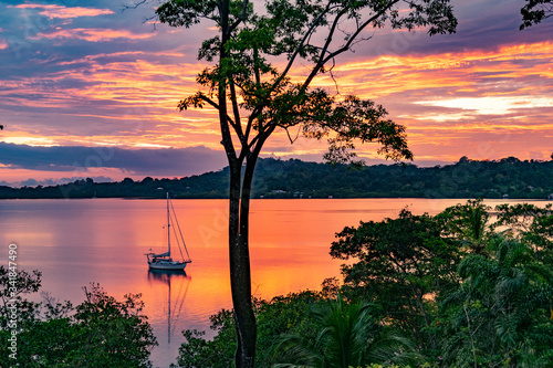 Sailboat anchored during a sunset in the tranquil Dolphin Bay, Panama