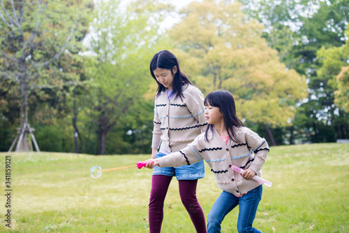 公園でしゃぼん玉を遊んでいる子供姉妹