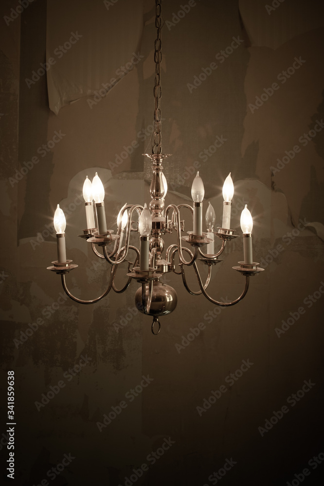 Old Broken Brass Chandelier in an Abandoned House with the Wall Paper peeling off the walls Old Broken Brass Chandelier in an Abandoned House with the Wall Paper peeling off the walls