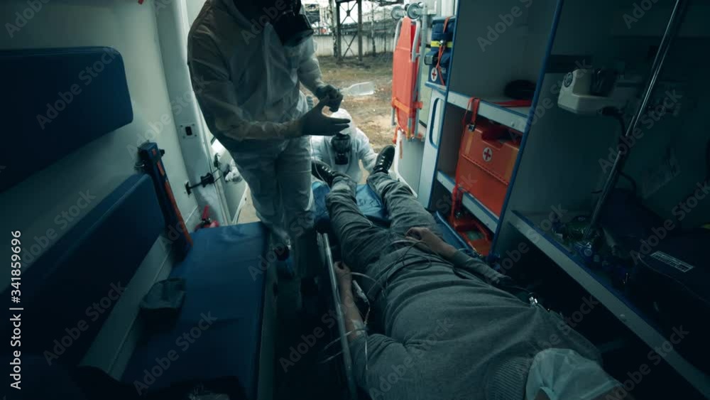 Ambulance workers take care of a male patient in a car. Ambulance workers take care of a male patient in a car.