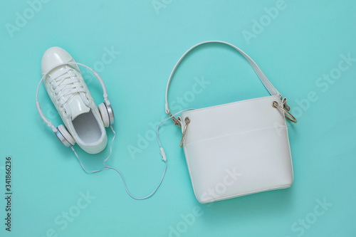 White sneakers with an earpiece and a white leather bag on a light background. Flat lay.