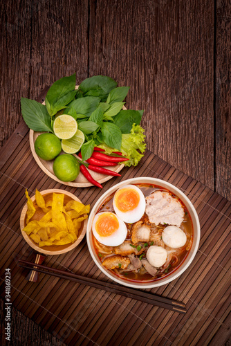 Spicy Noodles with Egg  fish ball and minced pork  Spicy Pork noodle with Spicy soup on wood background.