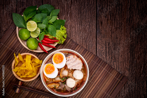 Spicy Noodles with Egg, fish ball and minced pork, Spicy Pork noodle with Spicy soup on wood background.