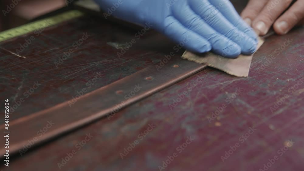 Professional tanner is sharpening a belt. The leather master is making a belt Professional tanner is sharpening a belt. The leather master is making a belt