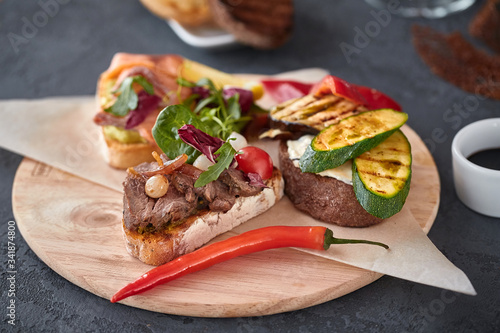 Assorted Bruschetta with fish, meat, vegetables and cheese on a wooden Board. Traditional Italian appetizer or appetizer, antipasto
