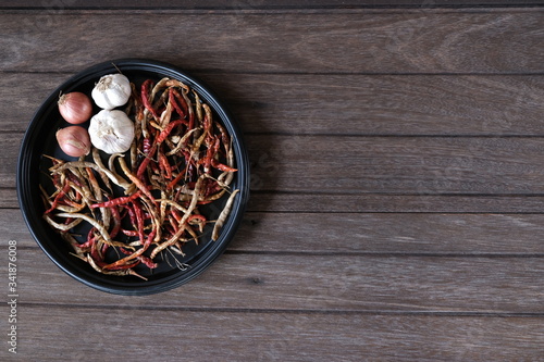 Dried chilis and garlic cloves, shallots in black dish on the old wood table on top view.