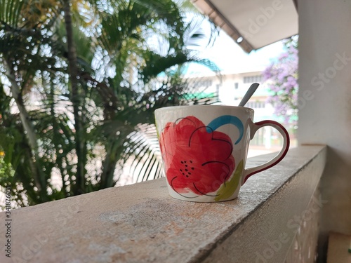 Red flower coffee cup, tea on concrete backrest and light ,blurred background