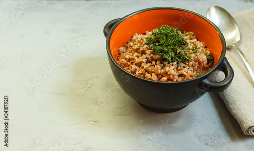Canvastavla Buckwheat porridge in a black and orange bowl with greens on a gray background w