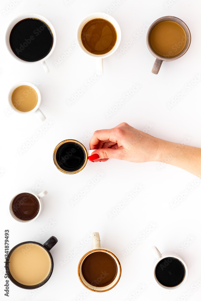 Coffee addiction. Mug in hand, many cups on white desk from above