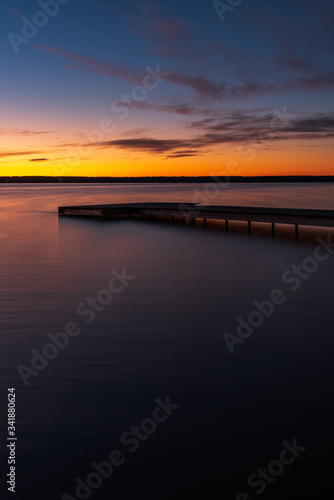 Sunset on the shore of the lake with a footbridge