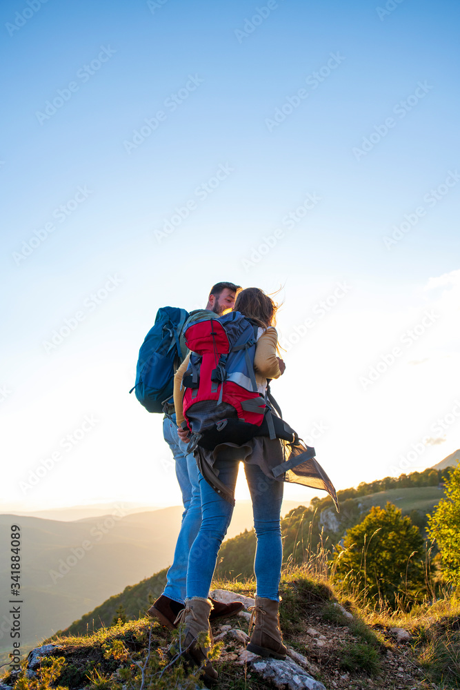 Hikers with backpacks relaxing on top of a mountain and enjoying the view of valley Hikers with backpacks relaxing on top of a mountain and enjoying the view of valley