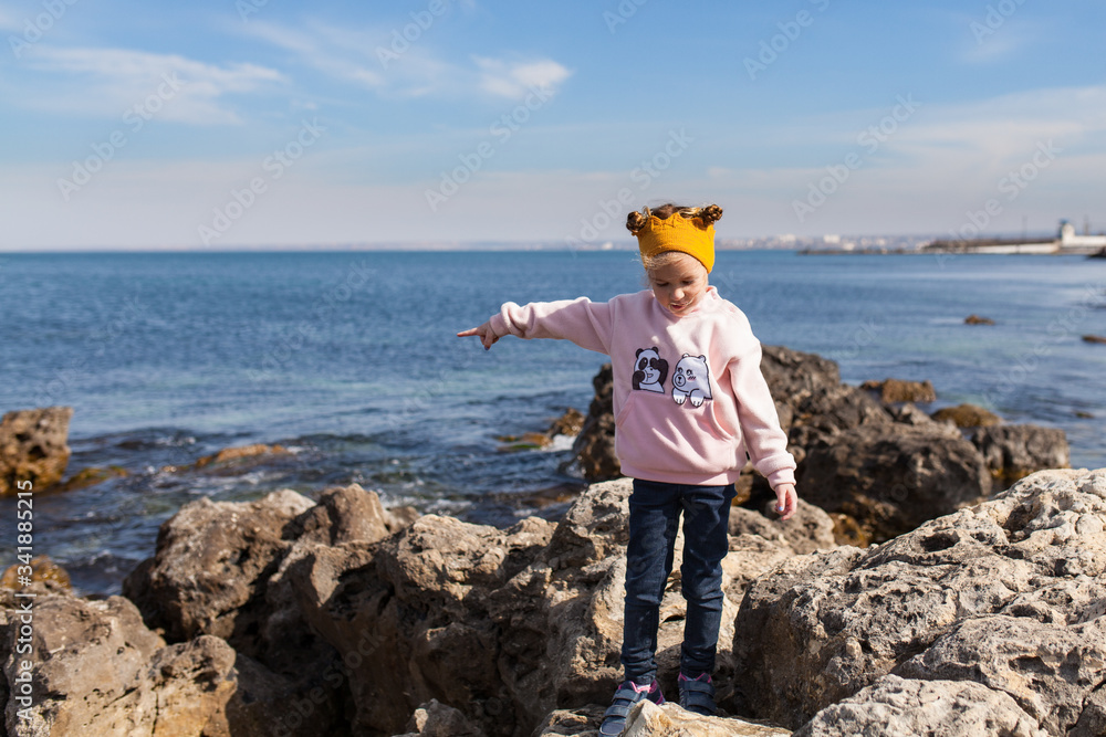 happy child walks on the sea coast, a child climbs stones