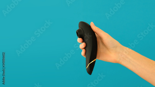 Woman holds vacuum clitoris stimulator isolated on blue background photo