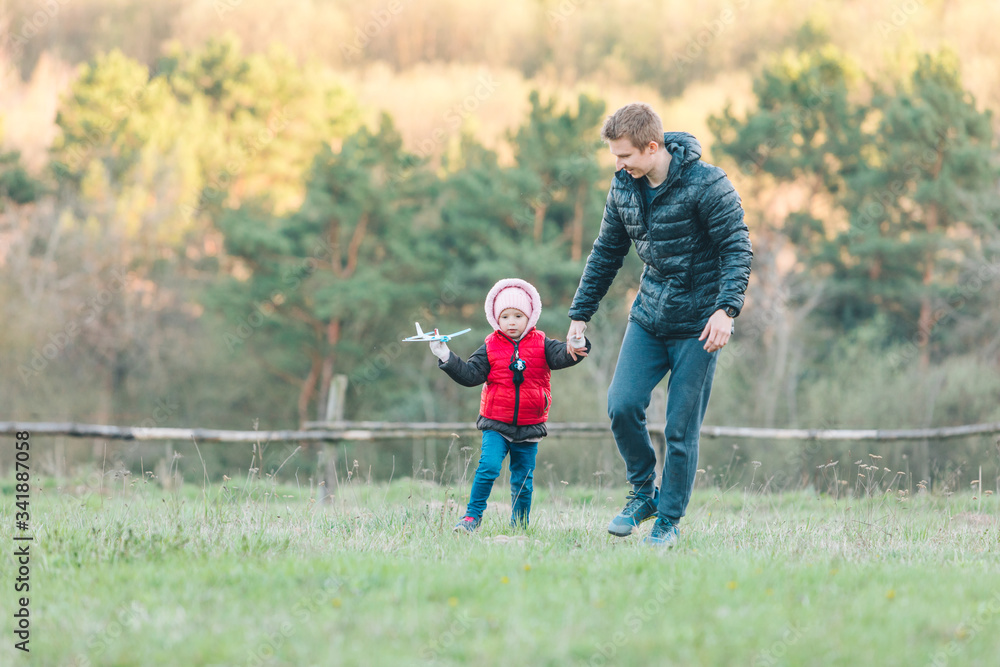Fototapeta premium father playing with toddler daughter at field with toy plain