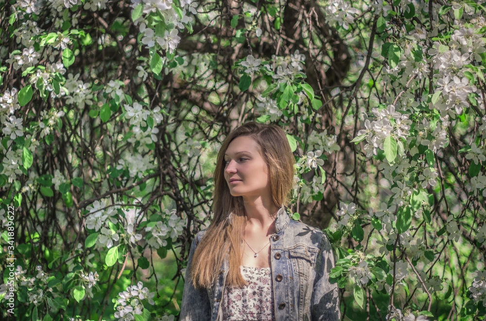 Woman posing on a background of a large blooming white flowers tree Woman posing on a background of a large blooming white flowers tree