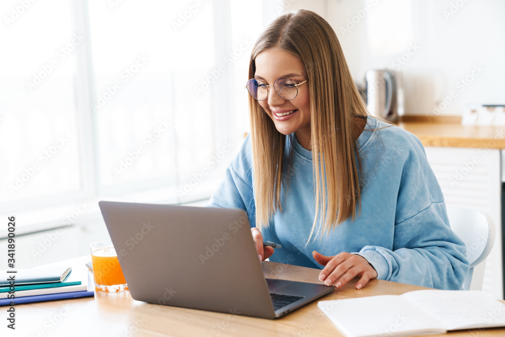 Image of cheerful charming woman smiling while working with laptop Image of cheerful charming woman smiling while working with laptop