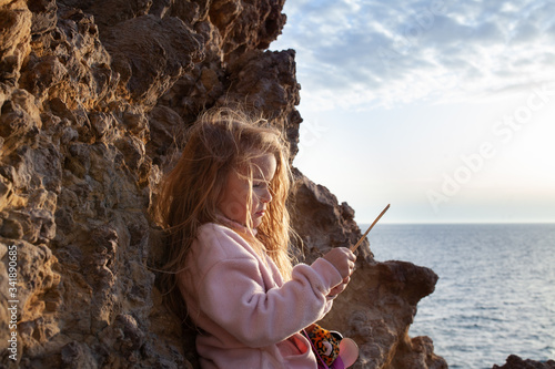 portrait of a beautiful girl with long hair on a background of white rock walking a happy child photo