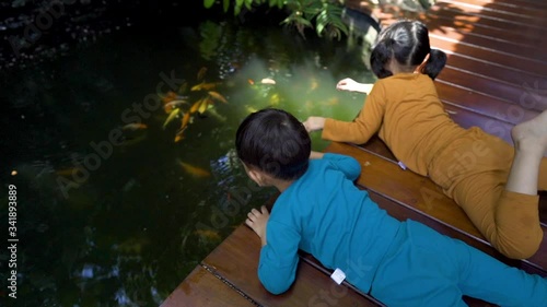 Two asian 3-4 years old kids quarantine stay home good time smiling and happy feeding fish togetherin their home.Funny acitivity enjoy the time.