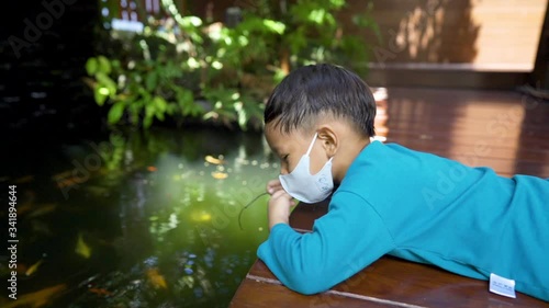 Two asian 3-4 years old kids quarantine stay home good time smiling and happy feeding fish togetherin their home.Funny acitivity enjoy the time.