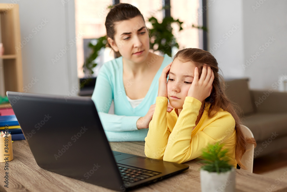 education, family and distant learning concept - mother and bored daughter with laptop computer doing homework together at home education, family and distant learning concept - mother and bored daughter with laptop computer doing homework together at home
