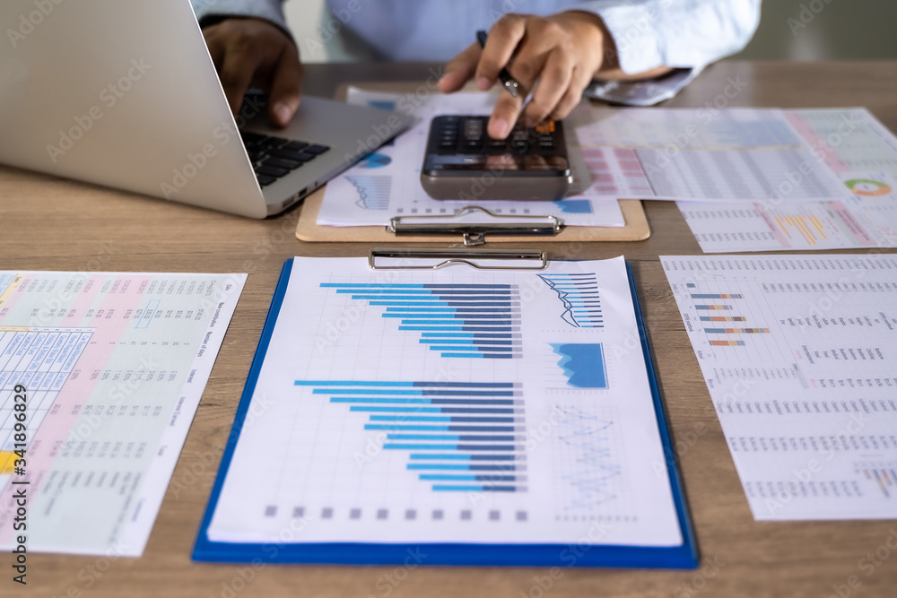Man Usingcalculator with money stack Financial Report- Business Accounting Concept accounting money with statistics graphs Man Usingcalculator with money stack Financial Report- Business Accounting Concept accounting money with statistics graphs