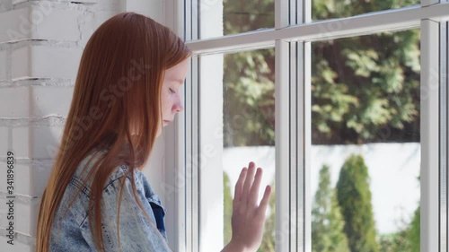 Sad girl walks to window