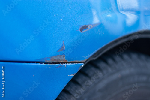 Fotografie Scratch on a bumper of a blue car on a public parking