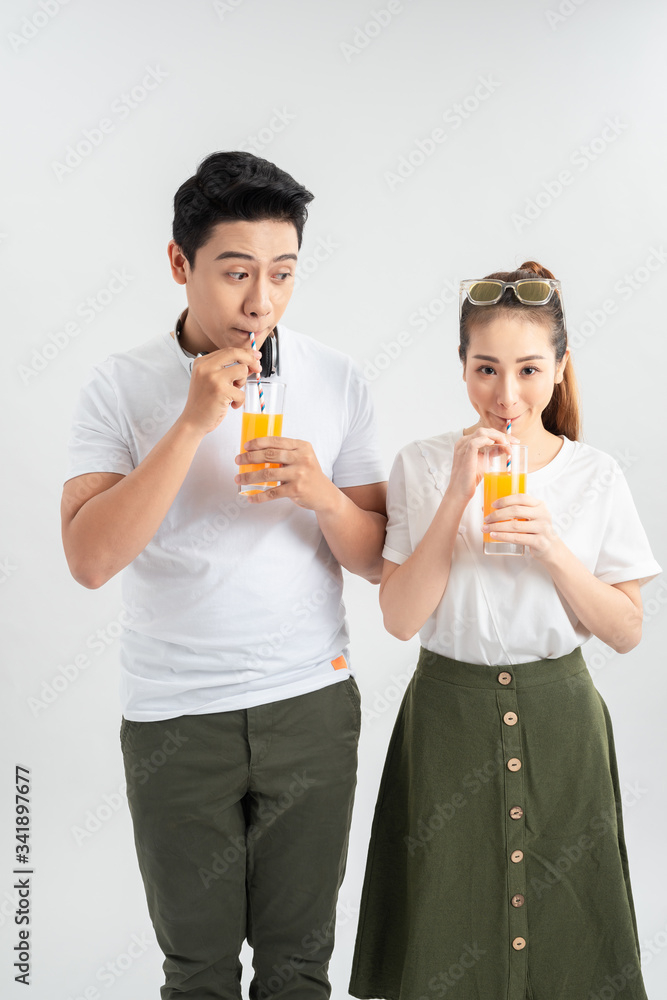 Happy young couple with glasses of orange juice isolated on a white background. Happy young couple with glasses of orange juice isolated on a white background.